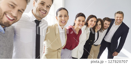 Group portrait of a happy smiling business people standing in a row and hugging on gray background. Group portrait of a happy smiling business people standing in a row and hugging on gray background. 127820707