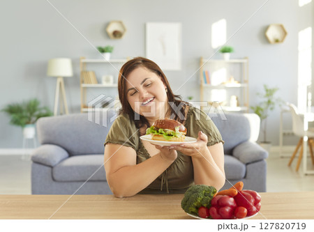Plus-Size Woman Deciding Between Healthy Food And A Burger At Home Plus-Size Woman Deciding Between Healthy Food And A Burger At Home 127820719
