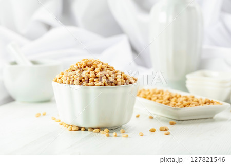 Pine nuts in white dish on a white background. Pine nuts in white dish on a white background. 127821546