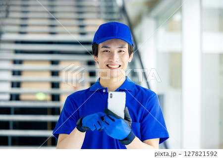 スマホを持つ配達員 127821592