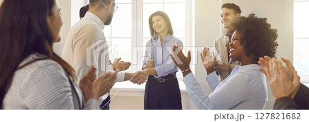 Joyful employees applauding, shaking hands with female colleague or coach after successful meeting. 127821682