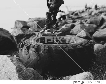 A Young Child Enjoying Skating on a Tire at the Scenic Shoreline Captured in Monochrome 127822012