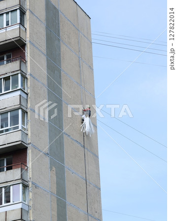 A worker is thoroughly performing window cleaning on a highrise building in the cityscape A worker is thoroughly performing window cleaning on a highrise building in the cityscape 127822014