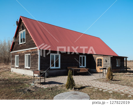 A Beautiful Rustic Wooden House with a Bright Red Roof Set in Open, Vast Landscape A Beautiful Rustic Wooden House with a Bright Red Roof Set in Open, Vast Landscape 127822019