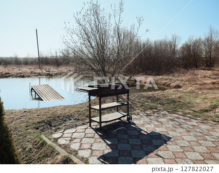 An Outdoor Barbecue Setup by a Tranquil Pond Creates an Idyllic Scene for Relaxation An Outdoor Barbecue Setup by a Tranquil Pond Creates an Idyllic Scene for Relaxation 127822027