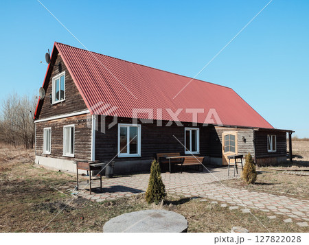 A Rustic Wooden House with a Vibrant Red Roof Nestled within a Serene Natural Landscape A Rustic Wooden House with a Vibrant Red Roof Nestled within a Serene Natural Landscape 127822028