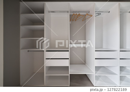 This is a modern design for a white closet that features both shelves and hangers effectively This is a modern design for a white closet that features both shelves and hangers effectively 127822189
