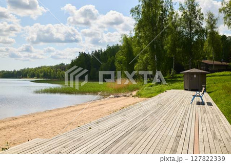 Experience a serene lakeside view featuring a beautiful wooden deck surrounded by lush greenery Experience a serene lakeside view featuring a beautiful wooden deck surrounded by lush greenery 127822339
