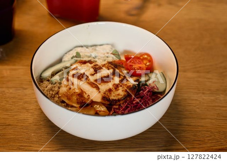 Indulge in a Savory Grilled Chicken Bowl adorned with Fresh Vegetables and Nutritious Quinoa 127822424