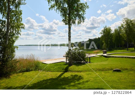 Experience a Serene Lakeside View Surrounded by Lush Greenery and a Beautiful Cloudy Sky 127822864