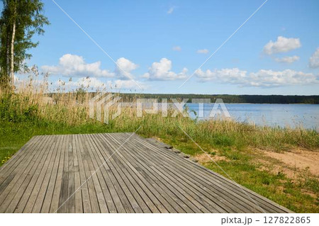 Experience a Serene Lakeside View featuring a Wooden Deck surrounded by Lush Greenery Experience a Serene Lakeside View featuring a Wooden Deck surrounded by Lush Greenery 127822865