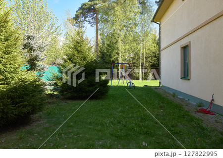 Tranquil and serene backyard scene featuring lush greenery along with a childrens play area 127822995