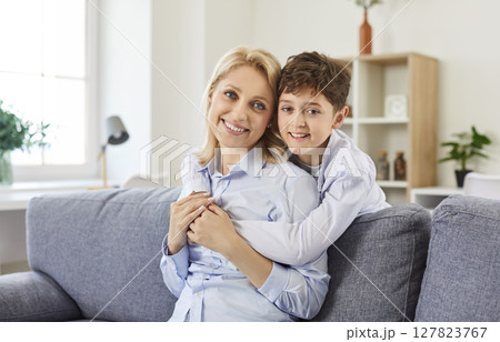 Portrait Of Happy Mother And Son Sitting On Sofa Embracing Together Portrait Of Happy Mother And Son Sitting On Sofa Embracing Together 127823767