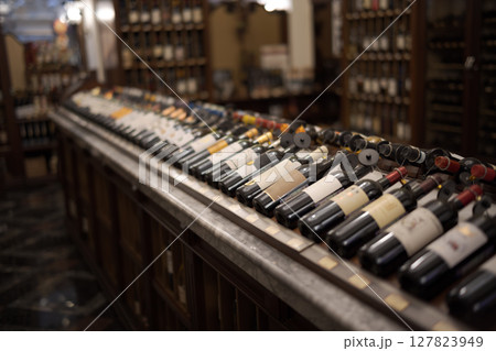 Row of wine bottles with dry red and white wine on wooden. Low depth of field. 127823949