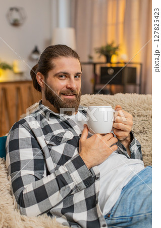 Young man lying with coffee mug at home, sofa calm, quiet break, easy smile, stress-free peace vibe Young man lying with coffee mug at home, sofa calm, quiet break, easy smile, stress-free peace vibe 127825423