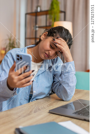 Upset displeased woman freelancer using smartphone reading bad news sitting at home office table 127825551