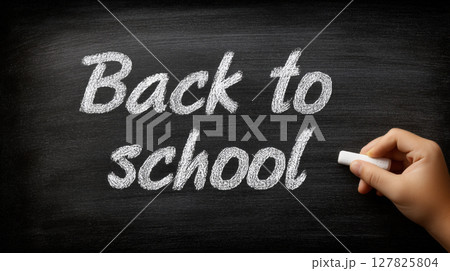 Back to school written in white chalk on blackboard with hand holding chalk 127825804