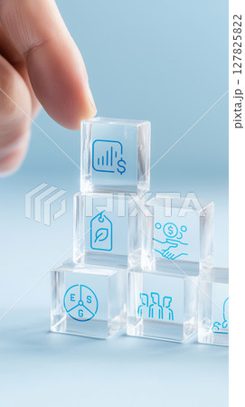 Person arranges translucent glass blocks with financial icons, symbolizing project management and strategy 127825822