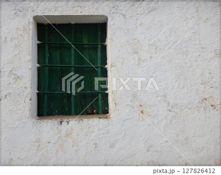 Old green wooden window in an old white facade 127826412