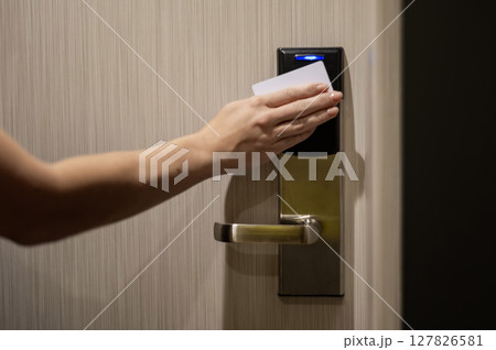 A woman opens an electronic lock with a card and enters a hotel room. A woman opens an electronic lock with a card and enters a hotel room. 127826581
