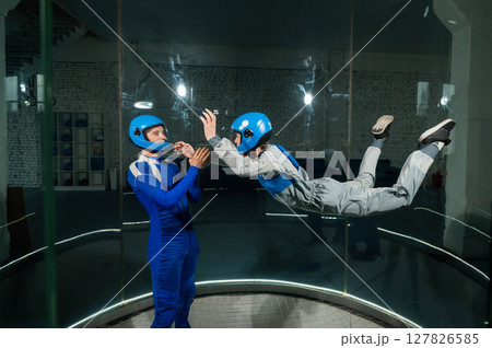 A male instructor teaches a woman how to fly in a wind tunnel. Free fall simulator. 127826585