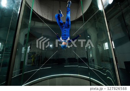 A man in overalls and a protective helmet enjoys flying in a wind tunnel. Free fall simulator 127826588