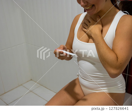A woman takes an express pregnancy test while sitting on the toilet. 127826641