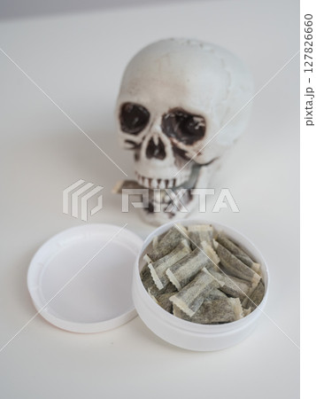 Skull Chewing Tobacco on a White Table. Skull Chewing Tobacco on a White Table. 127826660