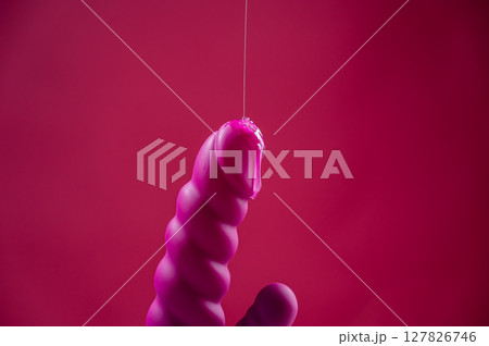 Lube pouring on pink dildo on pink background.  127826746
