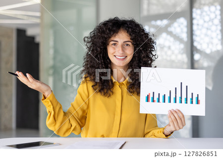 Webcam view, woman smiling and looking into camera, showing financial investment presentation, income graph and charts. Businesswoman at business meeting, remote conference. Webcam view, woman smiling and looking into camera, showing financial investment presentation, income graph and charts. Businesswoman at business meeting, remote conference. 127826851