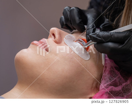 Caucasian woman undergoing eyelash lamination procedure.  127826905