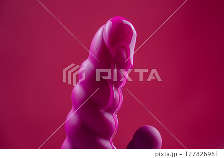 Lube pouring on pink dildo on pink background.  127826981