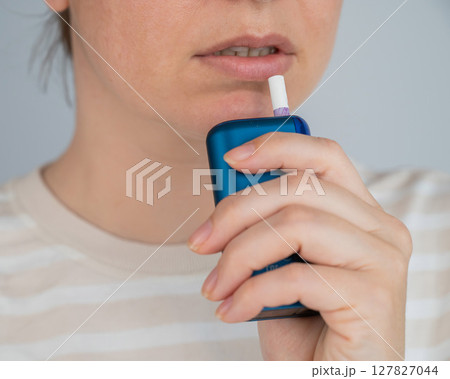 Caucasian woman smoking electronic cigarette. Tobacco heating system. 127827044
