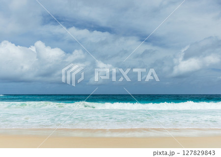 Mahe island, Seychelles. Tranquil ocean and sandy beach under a cloudy sky Mahe island, Seychelles. Tranquil ocean and sandy beach under a cloudy sky 127829843