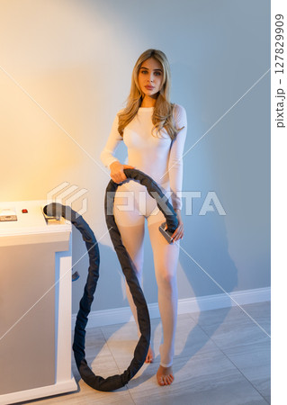 Woman in white suit for LPG massage. Anti-cellulite body care concept. Gray background 127829909