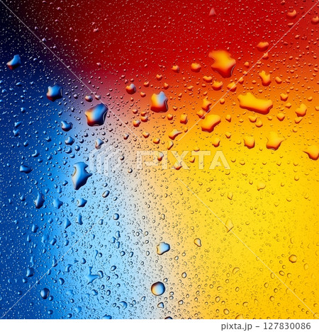 Colorful water droplets on vibrant blue, red, and yellow surface 127830086