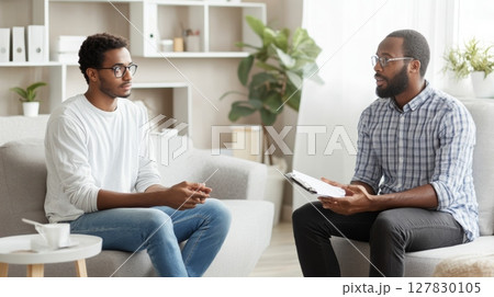 Psychologist providing support and guidance to a patient during a psychotherapy session, discussing mental health and emotional well being in a comfortable office setting Psychologist providing support and guidance to a patient during a psychotherapy session, discussing mental health and emotional well being in a comfortable office setting 127830105