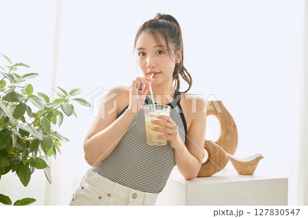 部屋ででレモネードを飲む夏の爽やかな若い女性 127830547