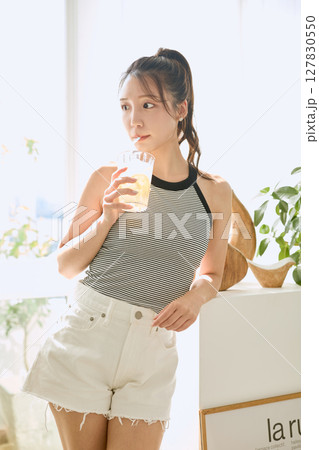 部屋ででレモネードを飲む夏の爽やかな若い女性 部屋ででレモネードを飲む夏の爽やかな若い女性 127830550