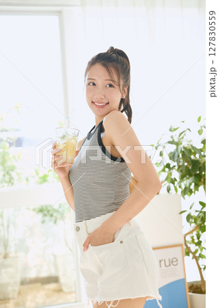 部屋ででレモネードを飲む夏の爽やかな若い女性 部屋ででレモネードを飲む夏の爽やかな若い女性 127830559