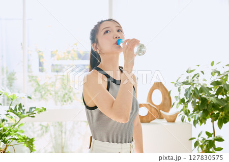 部屋ででラムネを楽しむ夏の爽やかな若い女性の笑顔 127830575