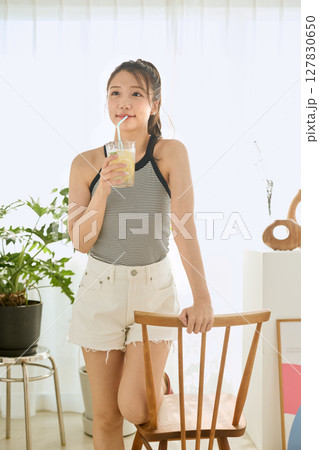 部屋ででレモネードを飲む夏の爽やかな若い女性 部屋ででレモネードを飲む夏の爽やかな若い女性 127830650