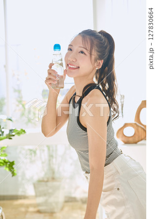 部屋ででラムネを楽しむ夏の爽やかな若い女性の笑顔 127830664