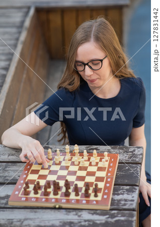 Caucasian woman playing chess outdoors.  127831442
