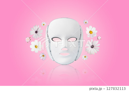 Cosmetic LED facial mask regenerative treatment on pink background with flowers cosmos, asters, and dahlias. Health and beauty of the face. Cosmetic LED facial mask regenerative treatment on pink background with flowers cosmos, asters, and dahlias. Health and beauty of the face. 127832113