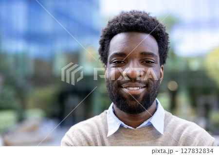 A smiling african american man stands outdoors, with a building visible in the background, showcasing a confident, professional demeanor. A smiling african american man stands outdoors, with a building visible in the background, showcasing a confident, professional demeanor. 127832834