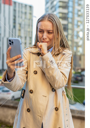 Upset businesswoman using smartphone browsing, loses becoming shocked bad news on downtown street 127833139