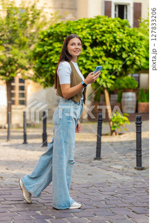 Tourist young woman using smartphone looking for search a way on map in navigator app outdoors 127833206