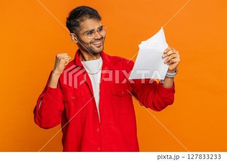 Happy Indian man open envelope take out letter reads, bank loan approve, great news, award, win Happy Indian man open envelope take out letter reads, bank loan approve, great news, award, win 127833233