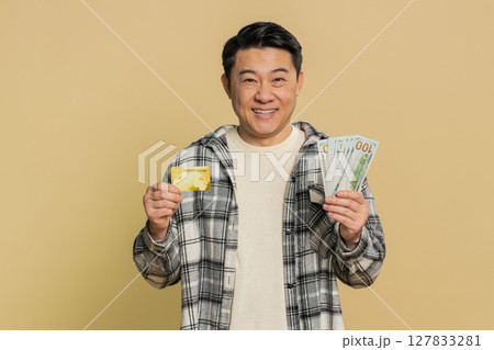 Happy Asian man showing plastic credit bank card and money dollar cash advertising taking loan Happy Asian man showing plastic credit bank card and money dollar cash advertising taking loan 127833281